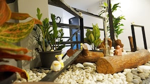 Una habitación con un tronco de madera, guijarros blancos y plantas en macetas.