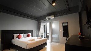 Una habitación de hotel moderna con una cama grande, un escritorio y un ventanal corredero que da a un balcón.