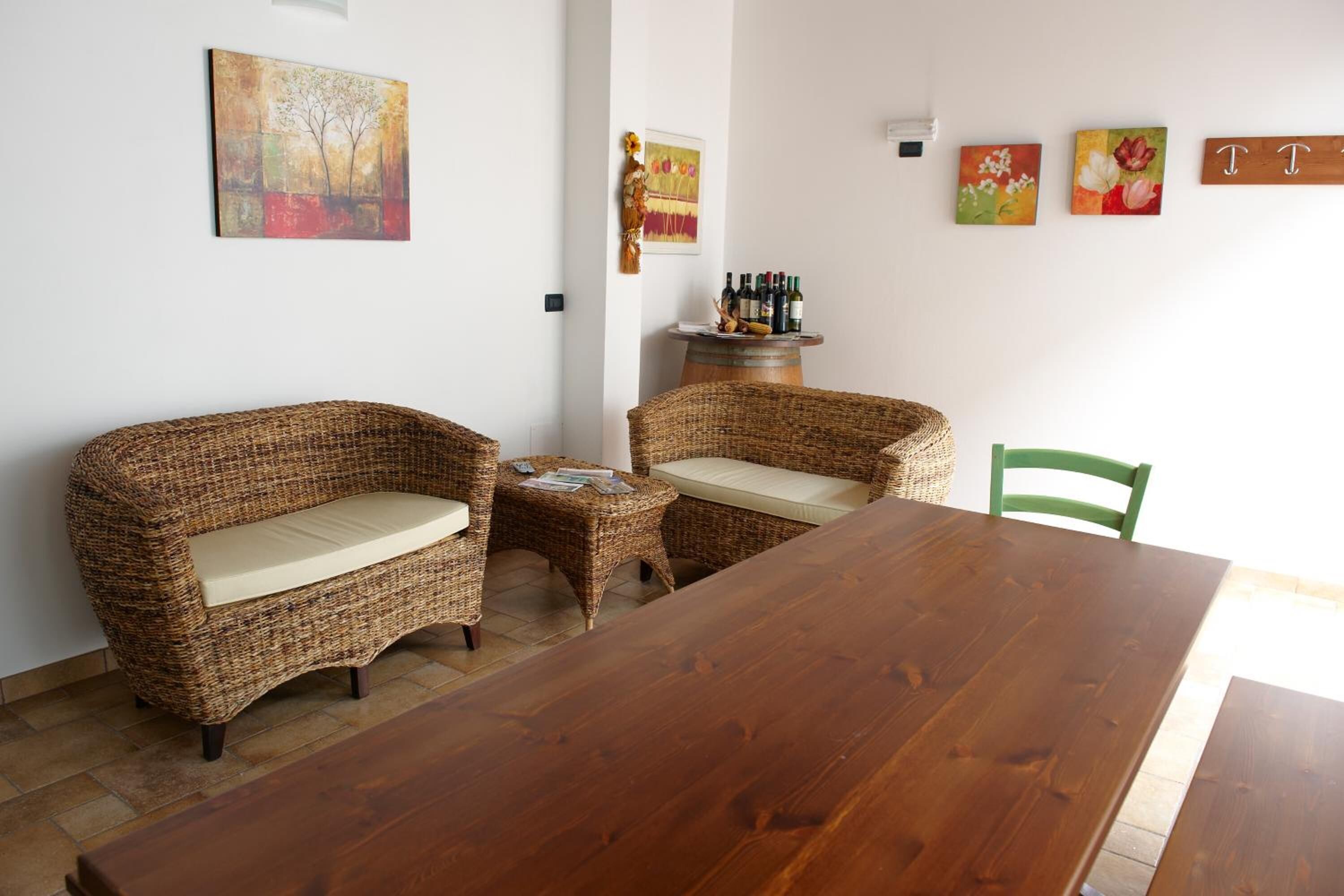 Un comedor con mobiliario de mimbre, una mesa de madera y decoración en la pared.