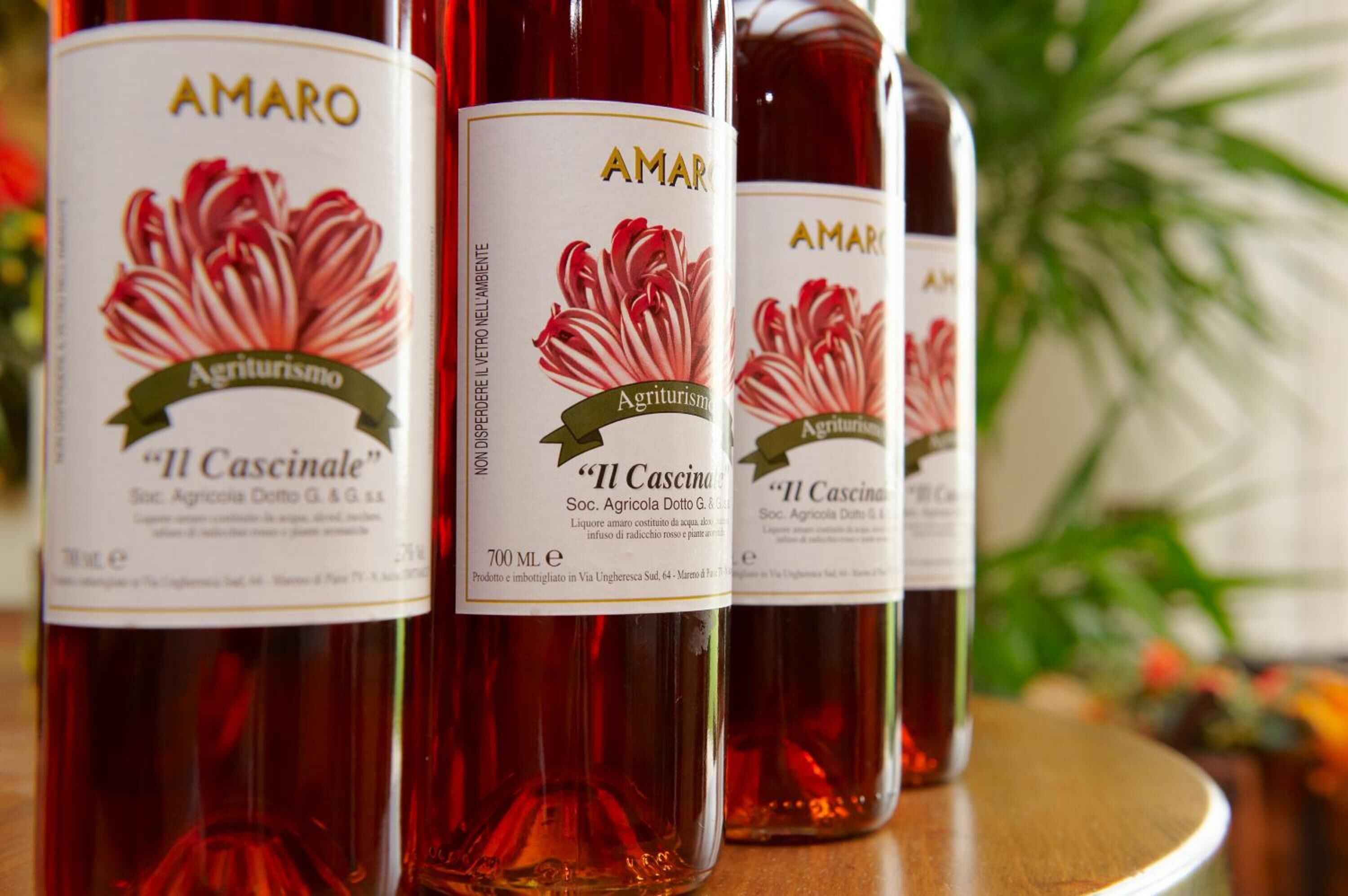 Tres botellas de vino Amar O Il Cascinale con etiquetas, sobre una superficie de madera.