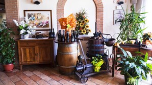 A rustic room with a wooden barrel, wine bottles, a vintage press, and potted plants. - Agriturismo Il Cascinale (Treviso)