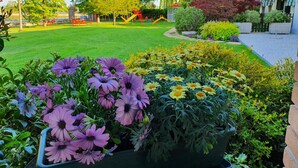 A well-maintained garden with various flower beds, a playground, and a building with a balcony. - Agriturismo Il Cascinale (Treviso)