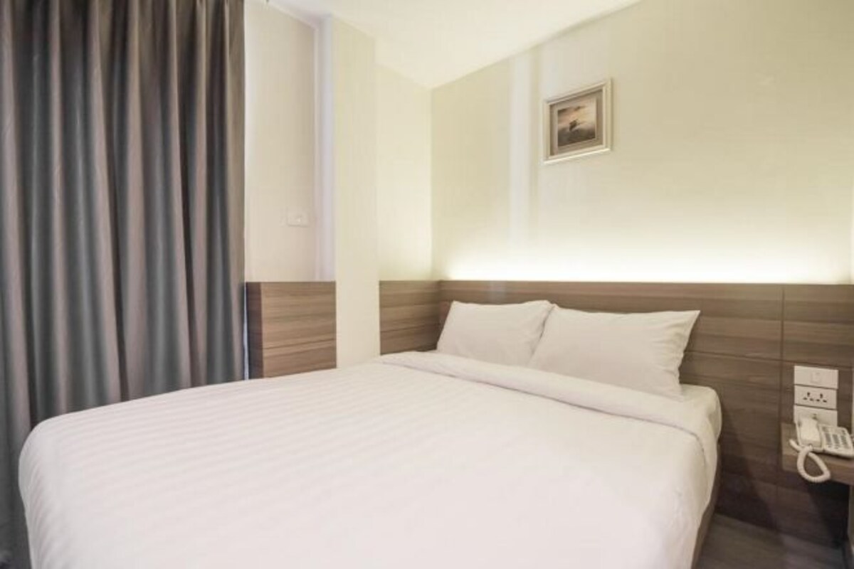 Una habitación de hotel con una cama grande, un teléfono en la mesita de noche y un cuadro en la pared.