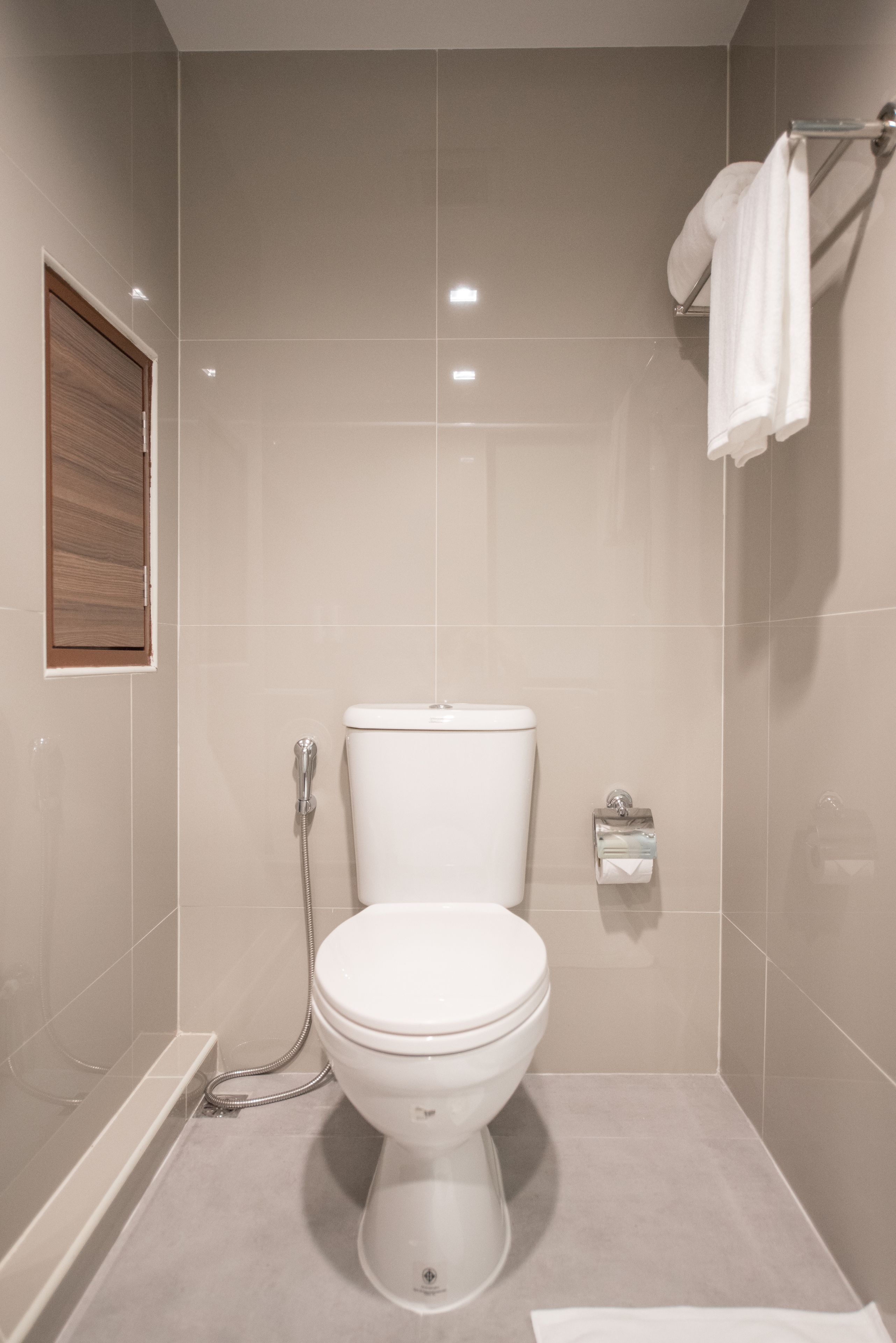 Een moderne badkamer met een toilet, douche en handdoekhouder.