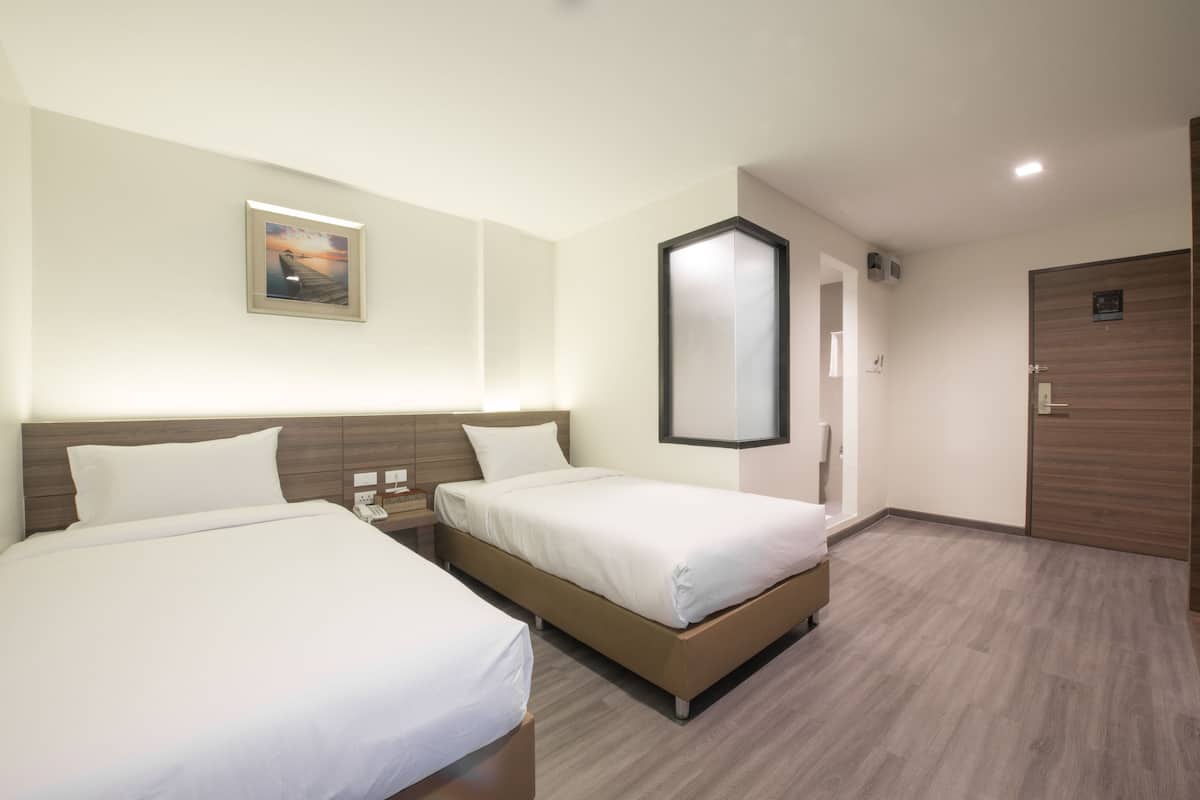 Habitación de hotel con dos camas, un espejo grande, un cuadro en la pared y una puerta de madera.