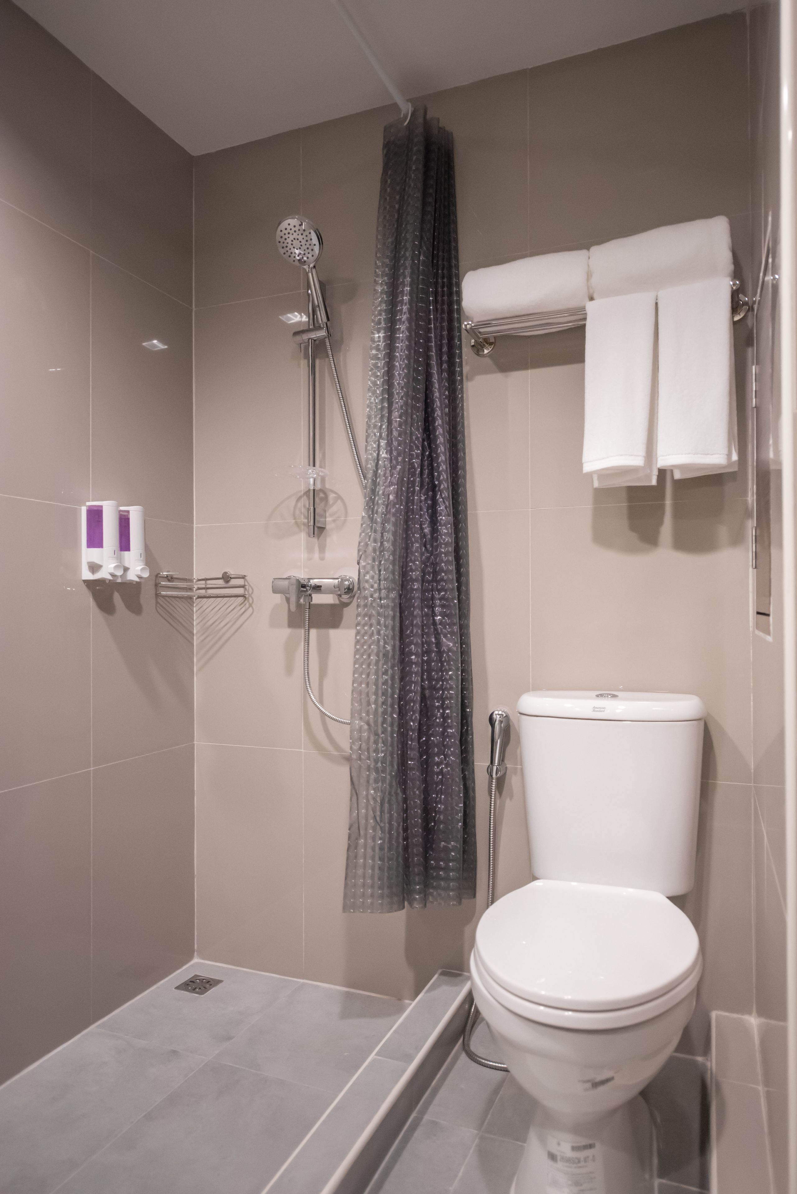 A modern bathroom with a shower, toilet, and towel rack.