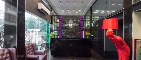 A modern lobby with a reception desk, plush seating, and a striking red sculpture.