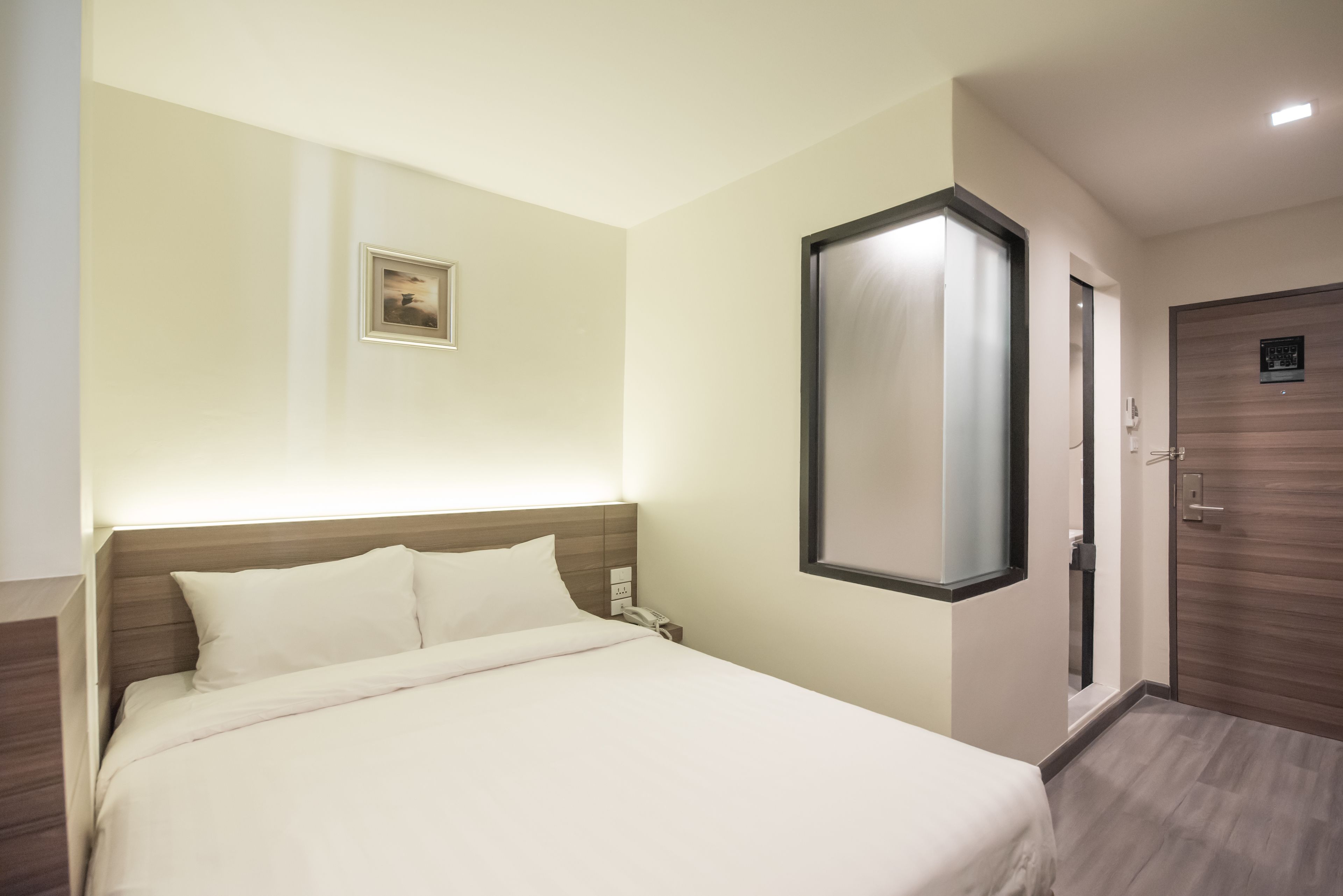 Een hotelkamer met een bed, nachtkastje en een deur.