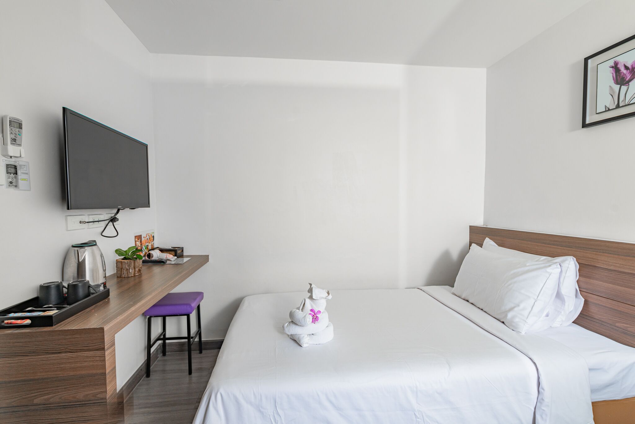 Ein Hotelzimmer mit Bett, Schreibtisch mit Kaffeemaschine, Fernseher und Wandthermostat.