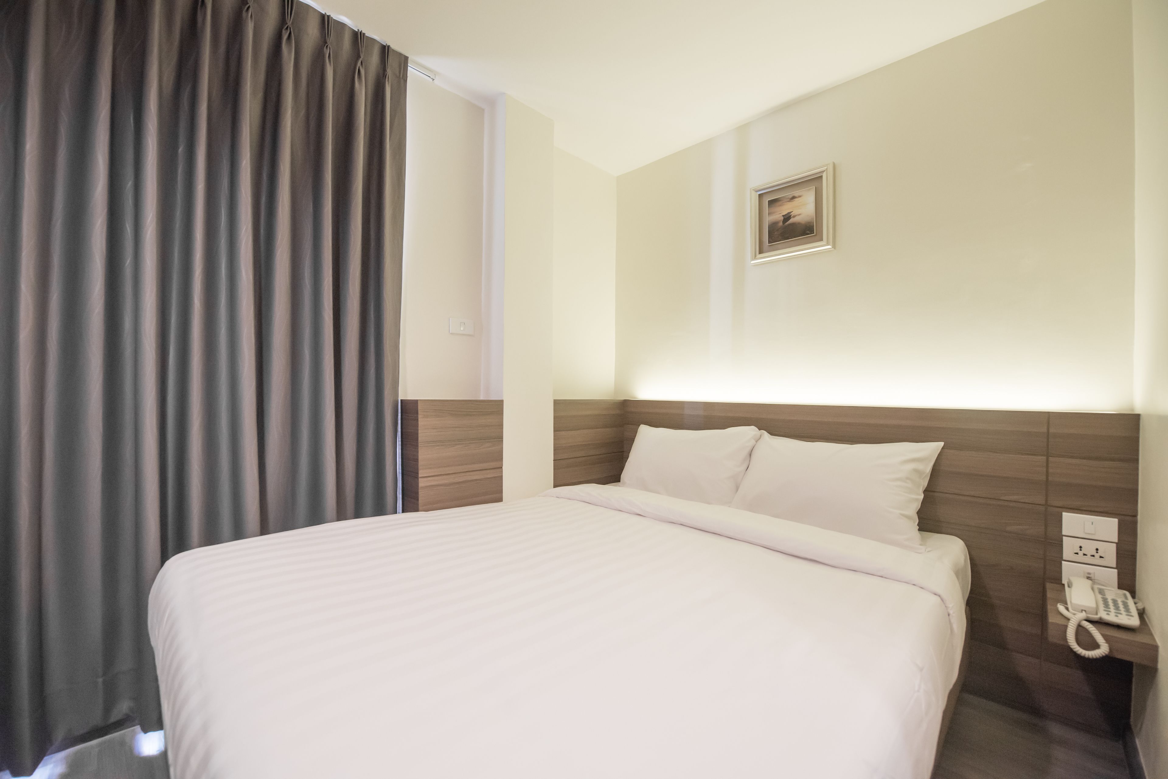 Une chambre d’hôtel avec un grand lit, un téléphone sur la table de chevet et un tableau au mur.