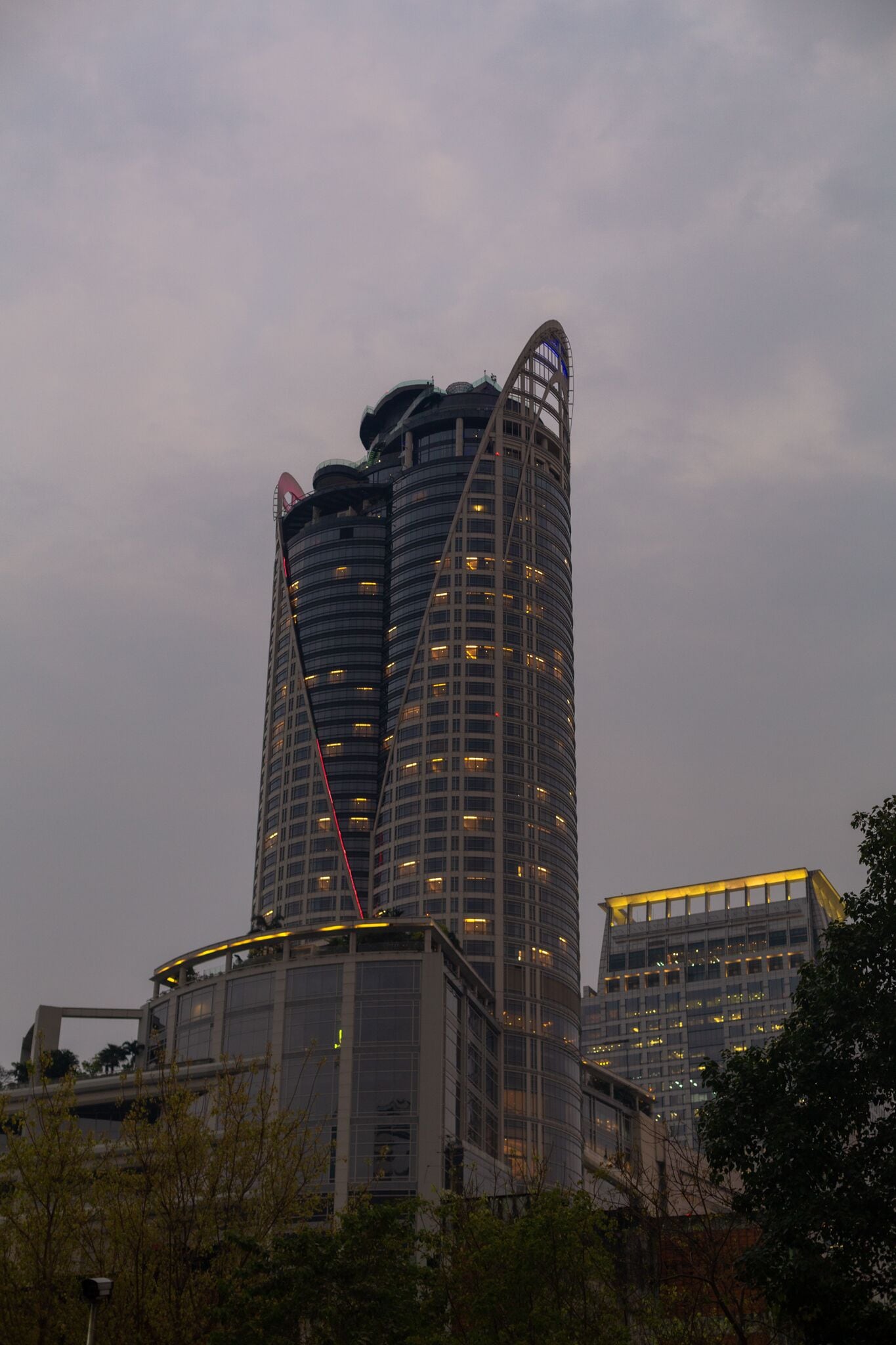 A tall, curved skyscraper with multiple floors and a distinctive top design.