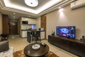 A modern living room with a flat-screen TV, a dining area, and a kitchen. - Jinjiang Peninsula Seasons Hotel (Qinhuangdao)