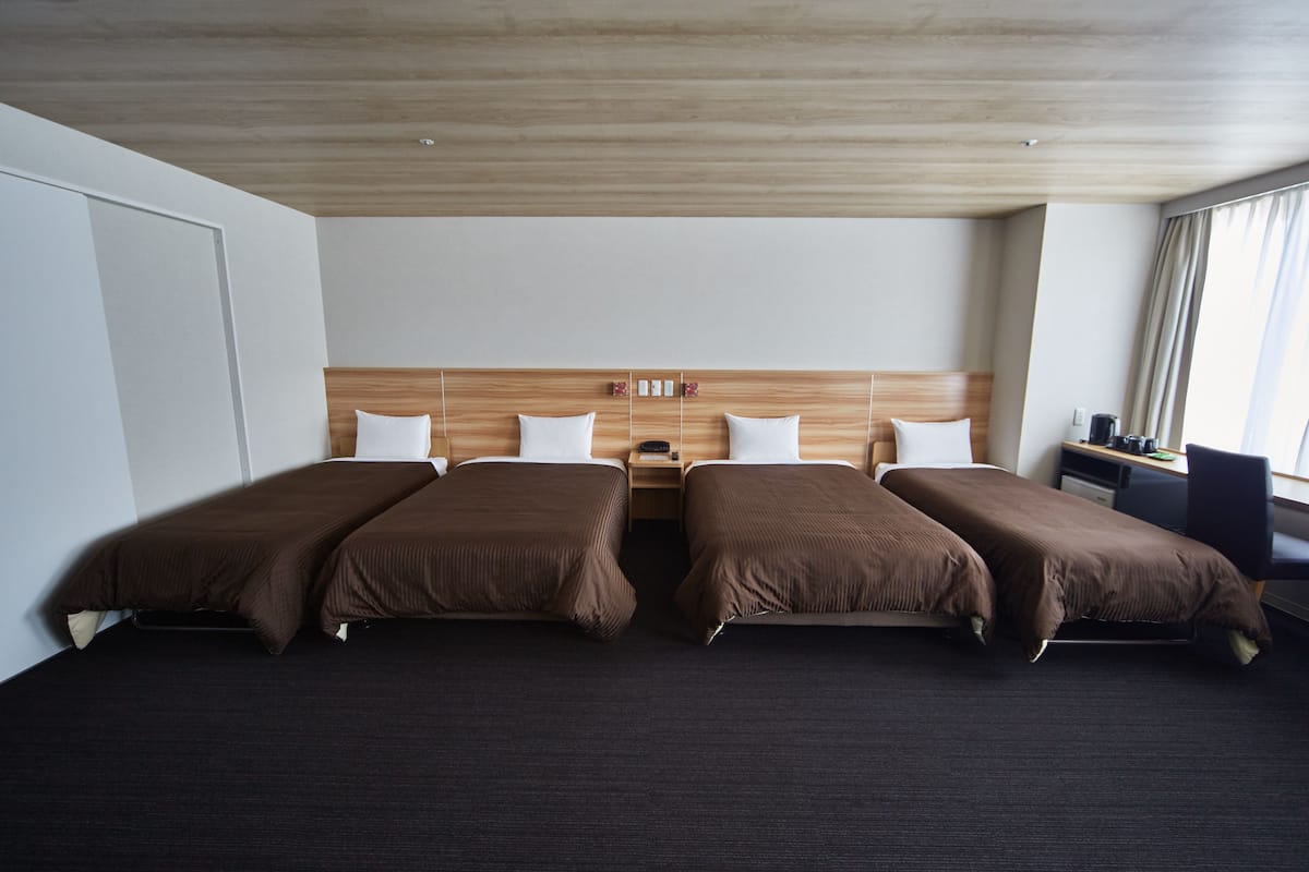 A hotel room with a large bed, a wooden headboard, a nightstand, and a desk with a chair.