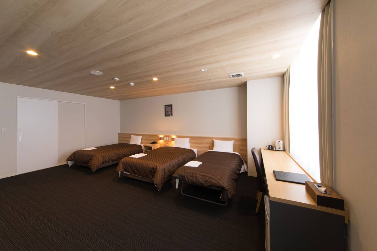 A hotel room with a large bed, a desk, and a window.