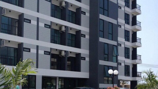 A multi-story building with balconies and air conditioning units. - Promsook Apartment (Chonburi)