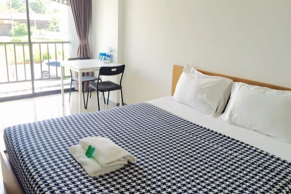 Habitación de hotel con una cama grande, un escritorio con silla y vistas al exterior.
