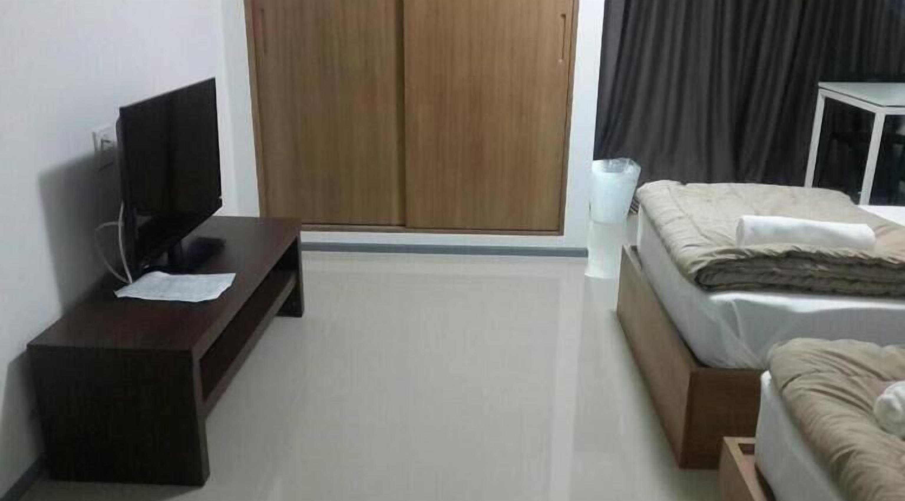 A hotel room with a bed, a TV on a stand, a wardrobe, and a bedside table.