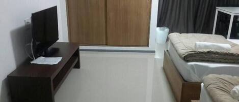 A hotel room with a bed, a TV on a stand, a wardrobe, and a bedside table.