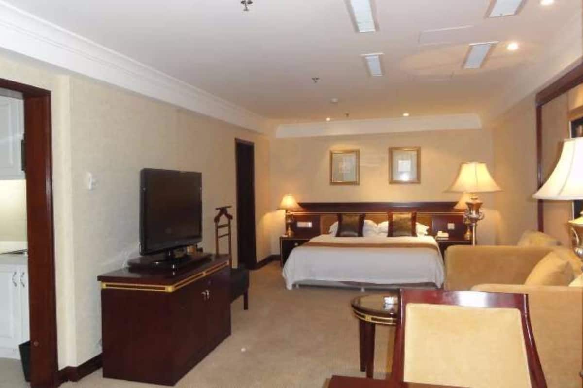 A hotel room with a bed, bedside tables, a TV, a desk, and a chair.