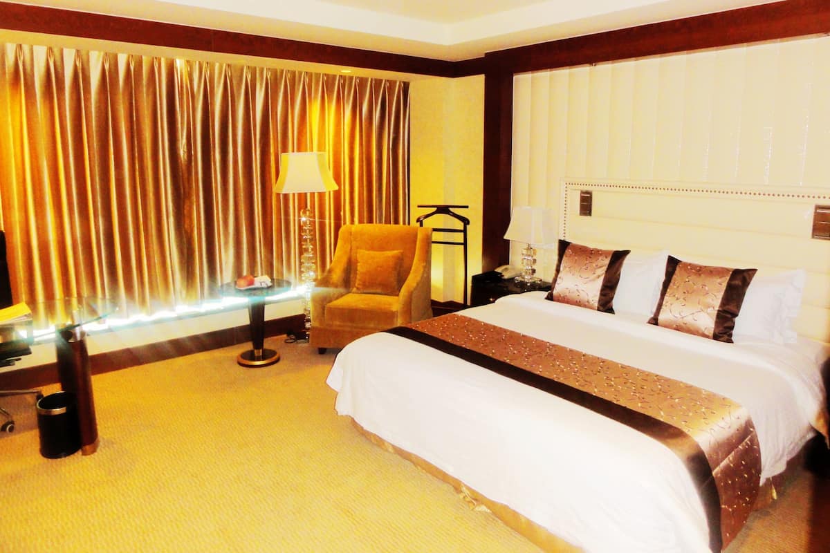 A hotel room with a large bed, a chair, a nightstand, and a lamp.