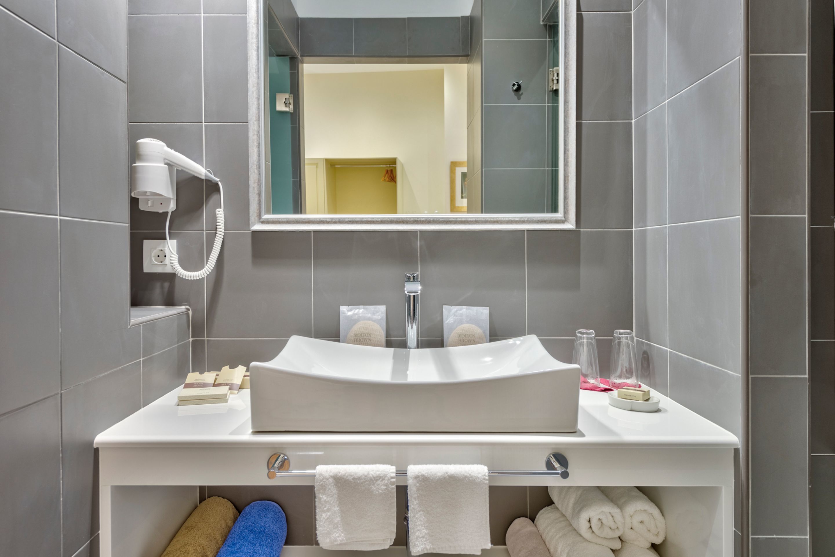 A modern bathroom with a white sink, mirror, and towel rack.