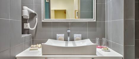 A modern bathroom with a white sink, mirror, and towel rack.