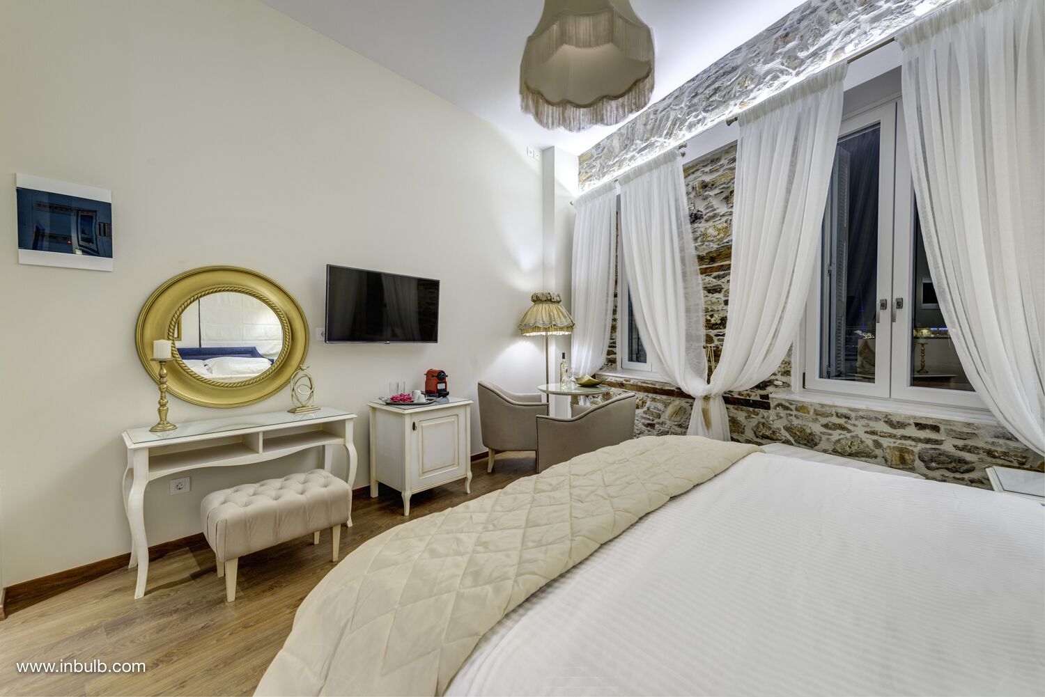 Un dormitorio con cama, escritorio, silla, televisor y ventana con cortinas.