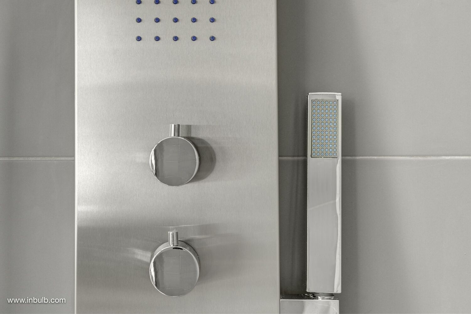 Una ducha moderna con panel de control, cabezal de ducha de mano y panel empotrado.