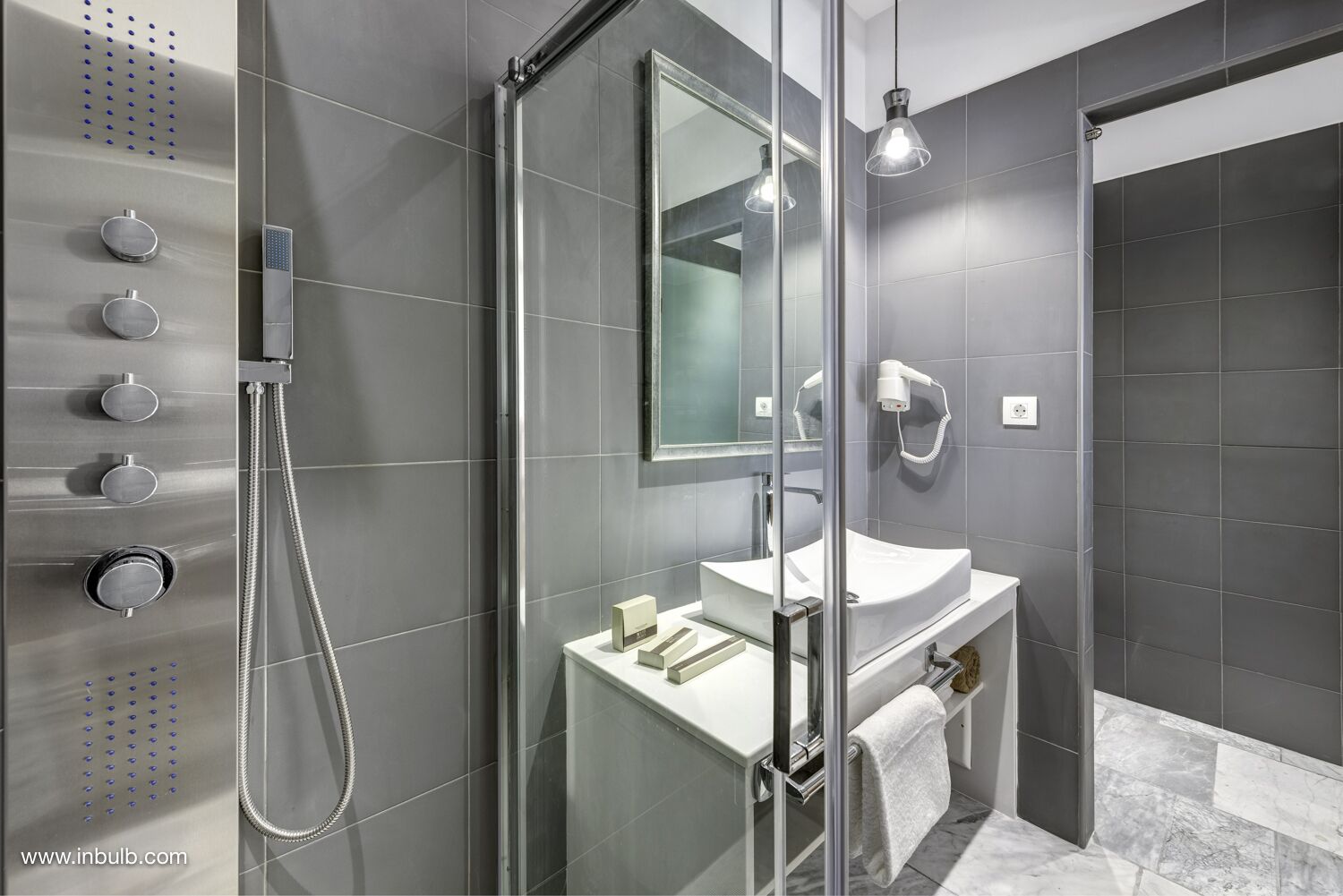 A modern bathroom with a glass-enclosed shower, a white sink, and a large mirror.