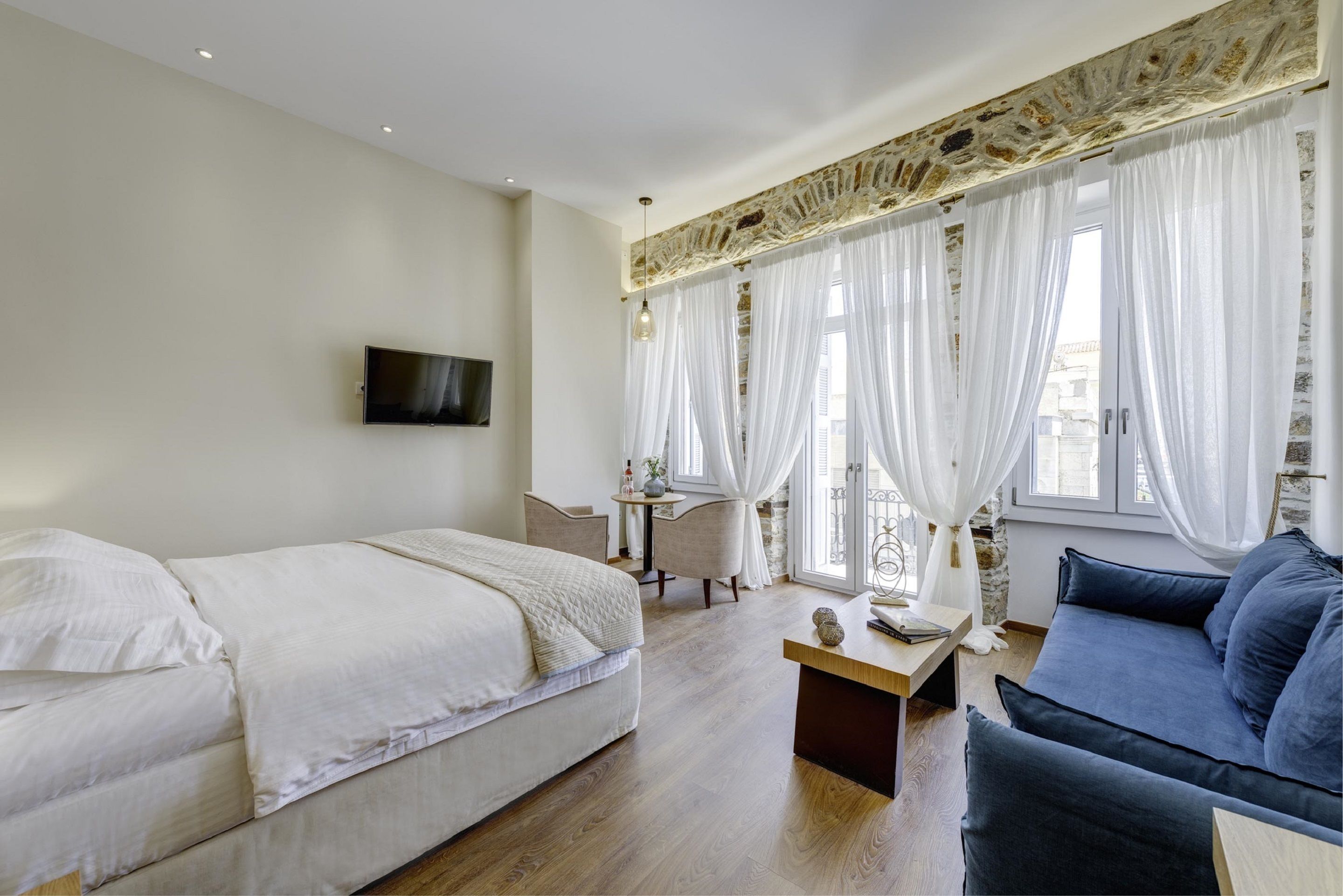 A hotel room with a bed, a sofa, a desk, and a TV.