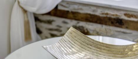 A white, round table with a metallic, ribbed bowl on it.