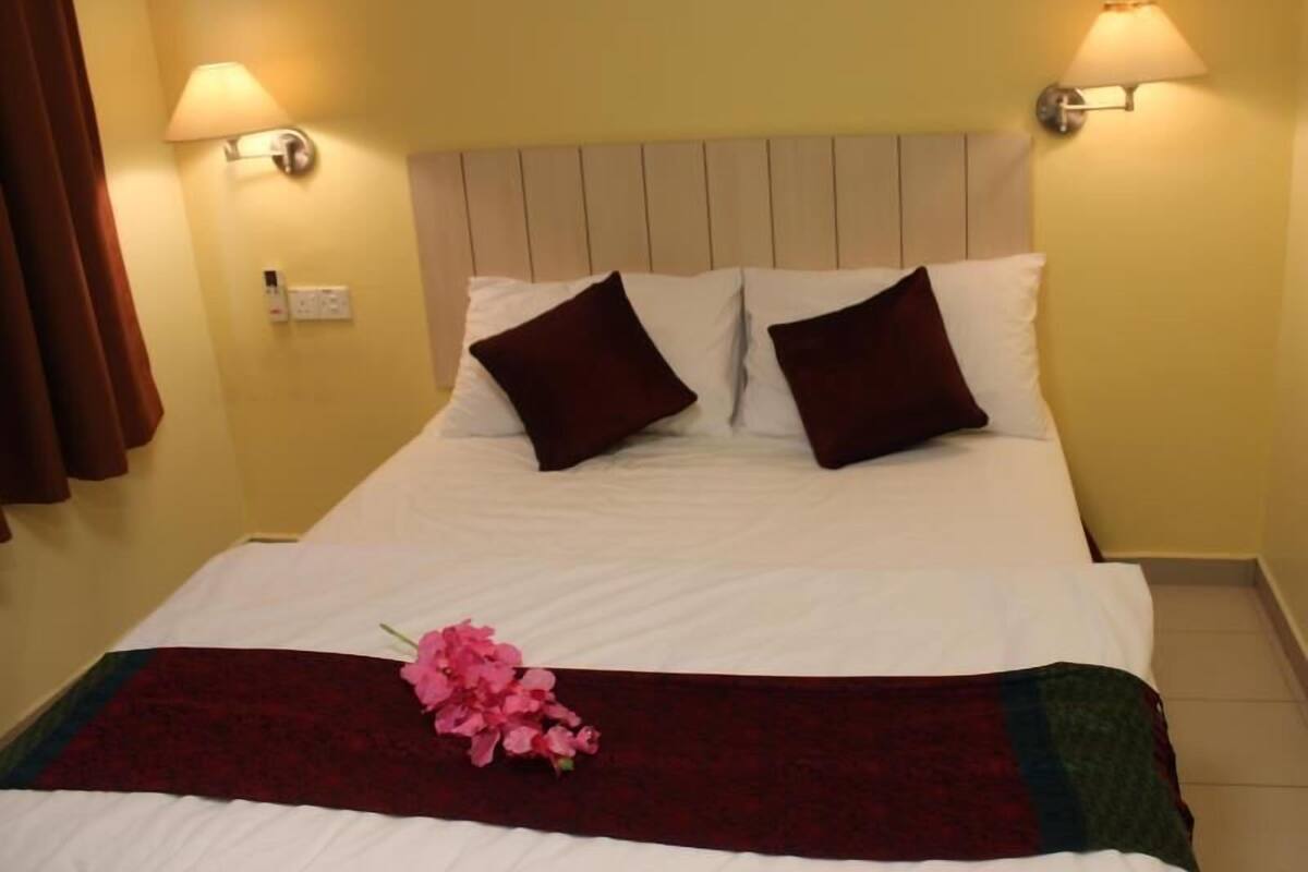 A hotel room with a bed, two wall-mounted lamps, and a floral decoration on the bed.