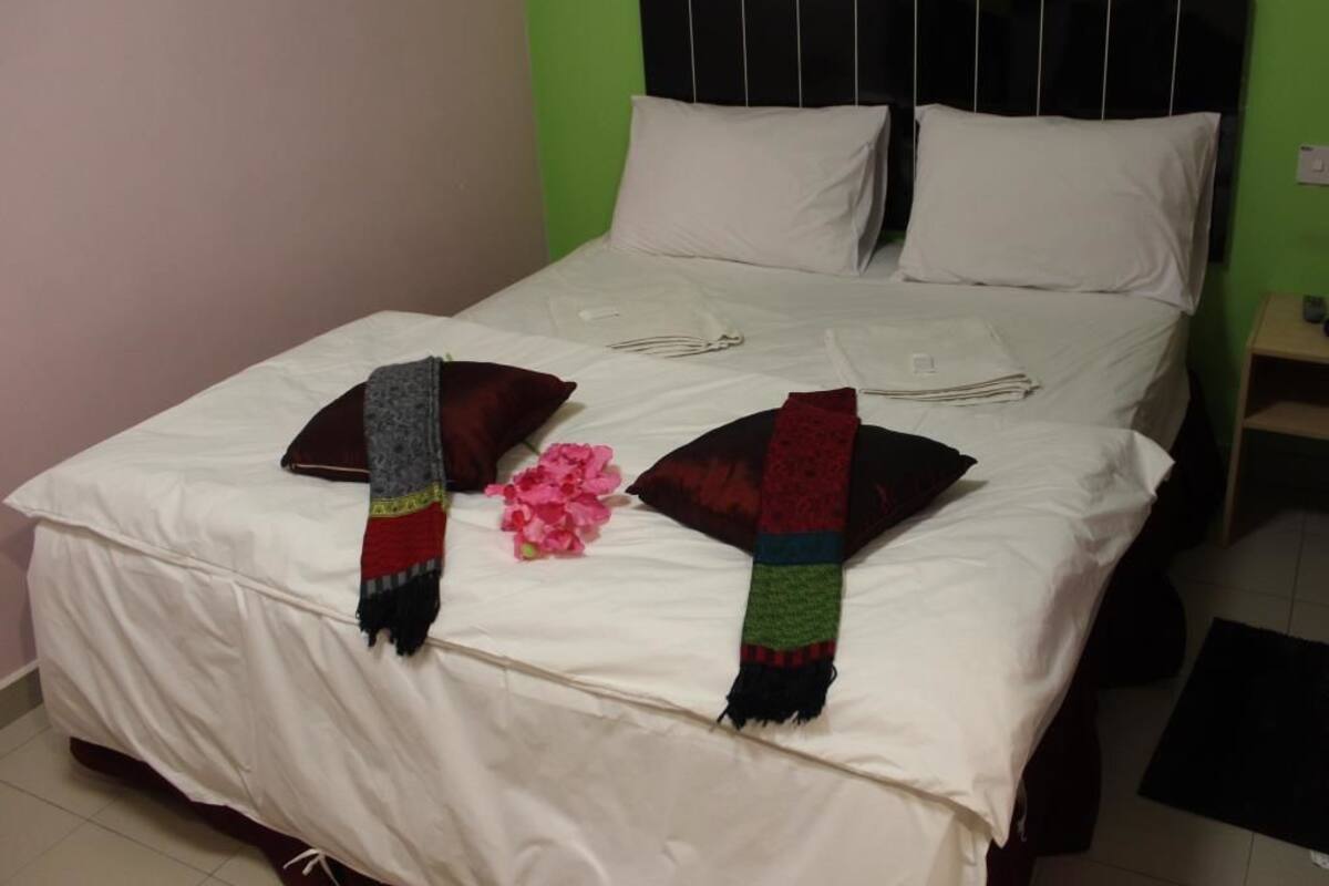 A bed with white bedding, two pillows, and two folded blankets.