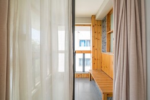 A corridor with a wooden bench, a window with a view, and a door with curtains. - Zen Tea House Seven Stars Park (Guilin)