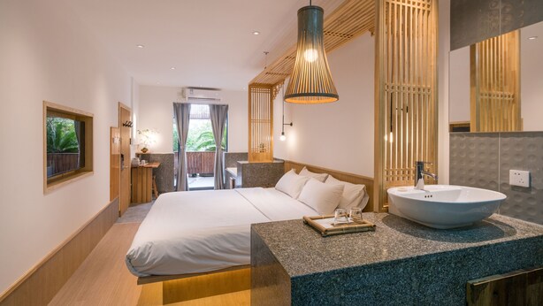 Ein modernes Hotelzimmer mit einem großen Bett, einem runden Waschbecken und Blick ins Freie.