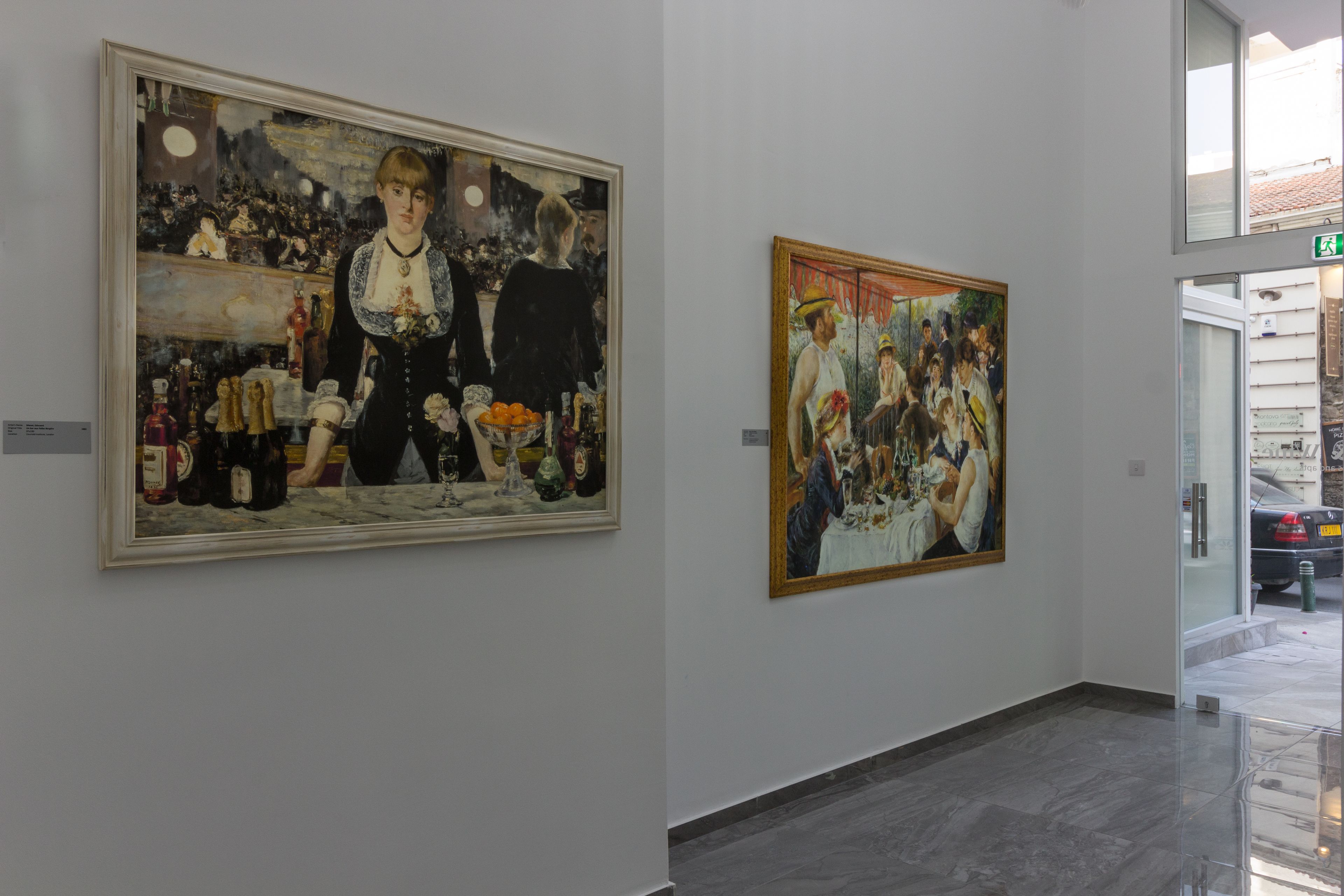 A gallery with two large paintings on the wall.