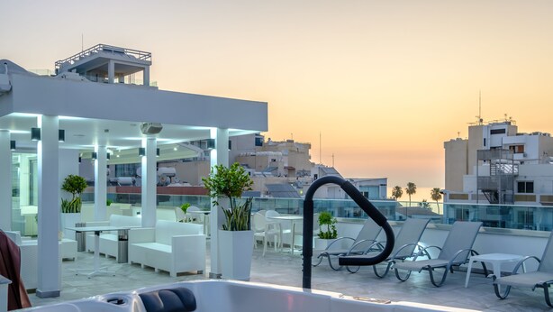 A rooftop terrace with lounge chairs, a hot tub, and a glass-enclosed area with tables and chairs. - Art & Wine Boutique Hotel (Larnaca)