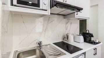 A modern kitchen with a built-in microwave, toaster, and kettle, along with a stainless steel sink and black induction cooktop.