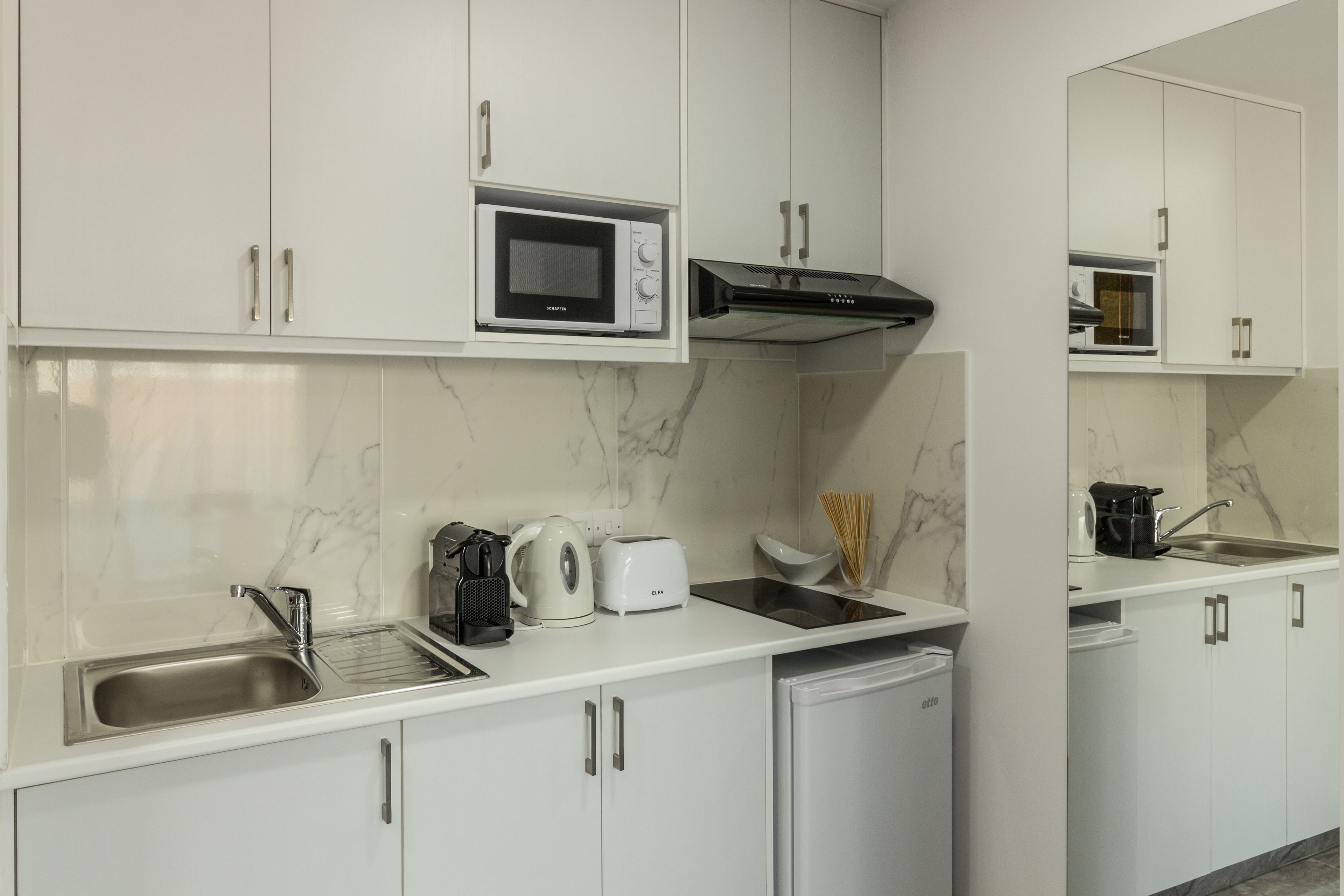 A modern kitchen with white cabinets, a microwave, a toaster, and a coffee maker.