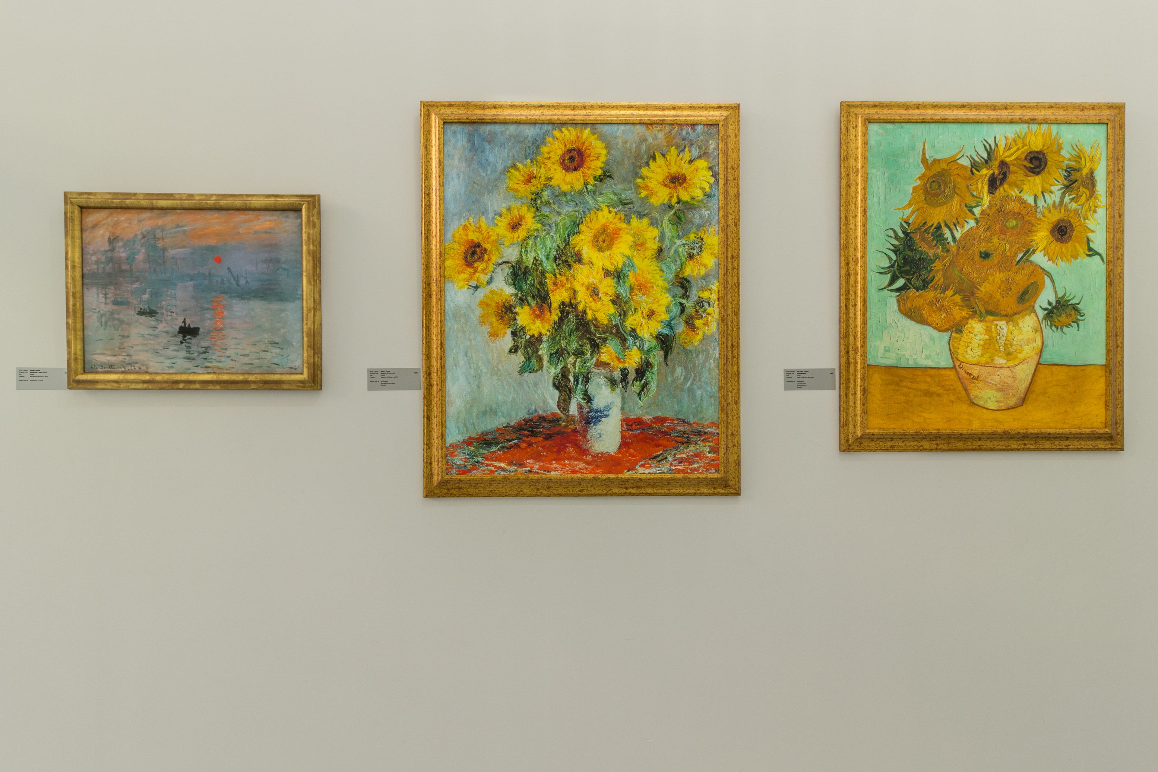 Three paintings of sunflowers on a wall.