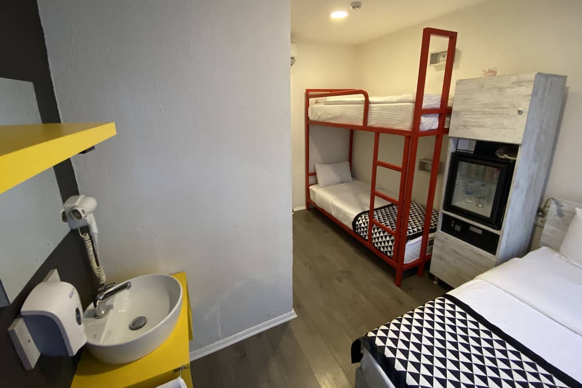 A bunk bed with a red frame, a white sink with a yellow countertop, and a small refrigerator.