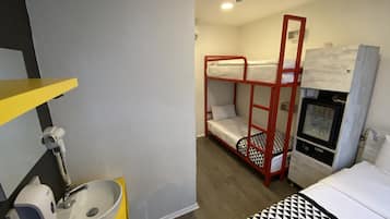 A bunk bed with a red frame, a white sink with a yellow countertop, and a small refrigerator.