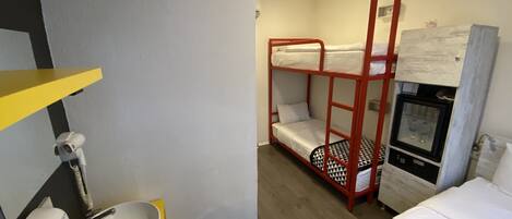A bunk bed with a red frame, a white sink with a yellow countertop, and a small refrigerator.