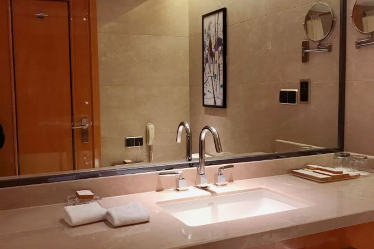Un baño moderno con un espejo grande, dos lavamanos y un perchero para toallas.