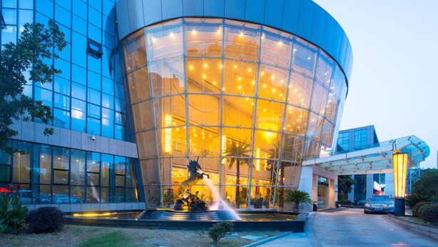 A modern building with a glass facade and a central courtyard with a water feature. - R-Sun International Hotel Wuxi (Wuxi)