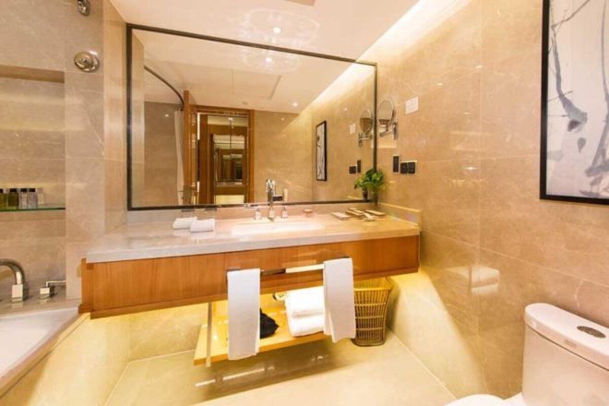Un baño moderno con un espejo grande, un tocador de madera y un inodoro.