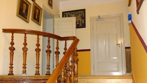 A wooden staircase with a handrail, leading to a white door. - Hummel Hostel (Weimar)