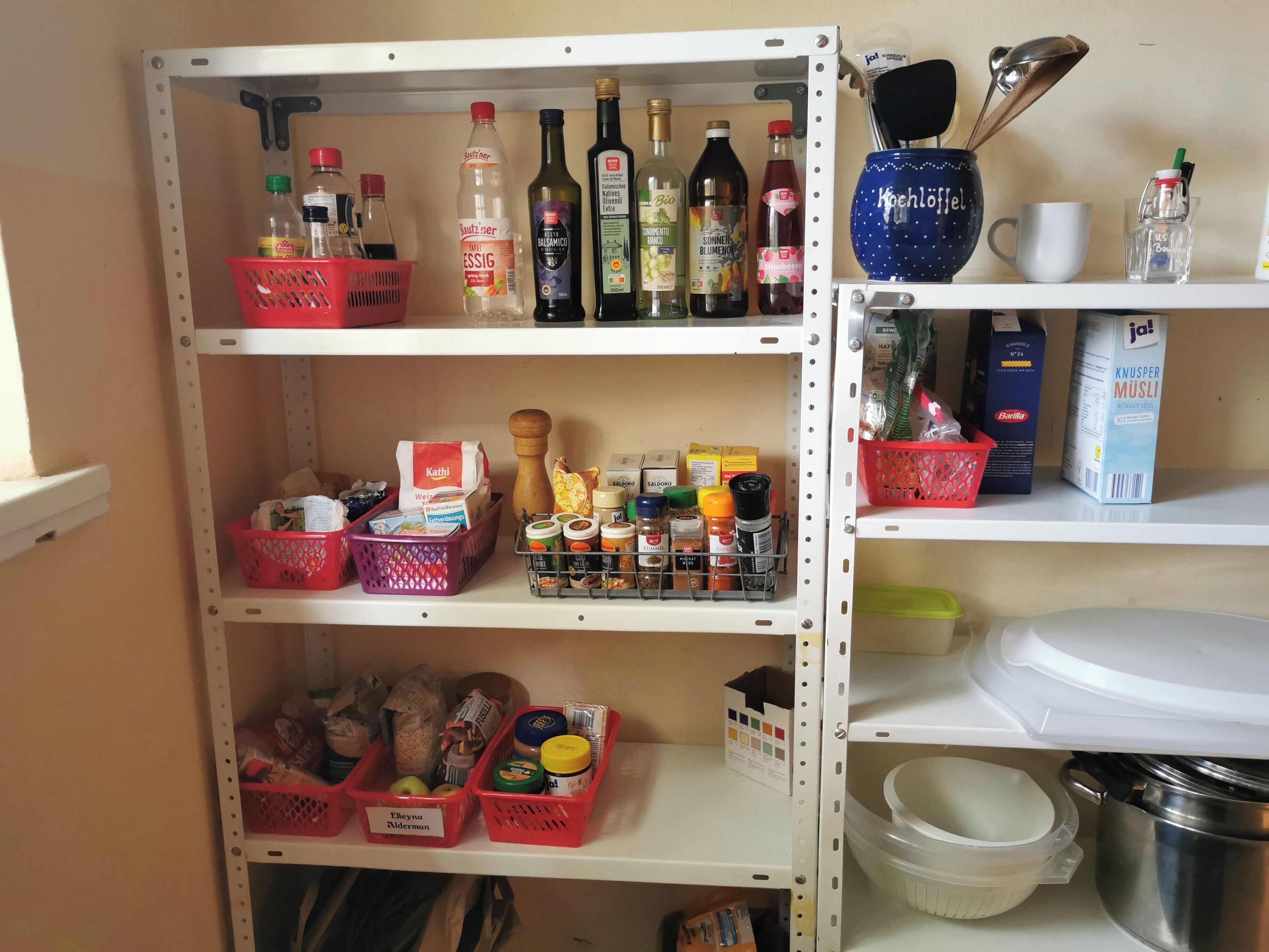 A well-organized pantry with shelves stocked with various food items, condiments, and kitchenware.
