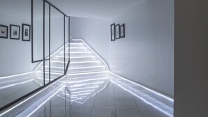 Un pasillo moderno con suelo reflectante, una escalera y cuadros enmarcados en las paredes.
