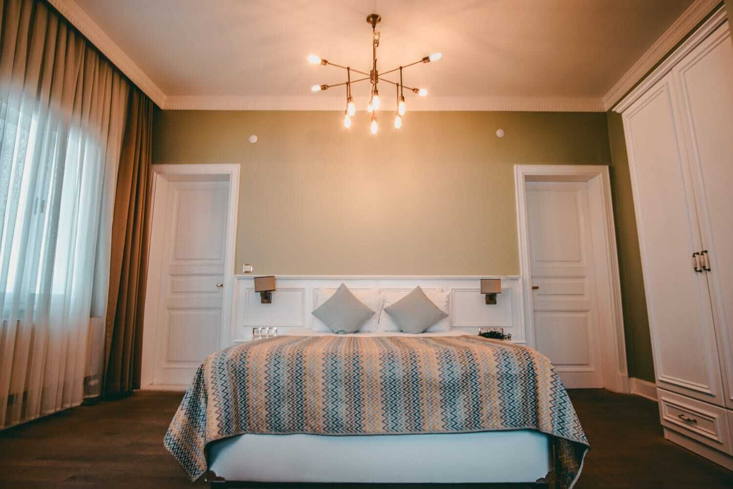 A bedroom with a bed, a chandelier, and a wardrobe.